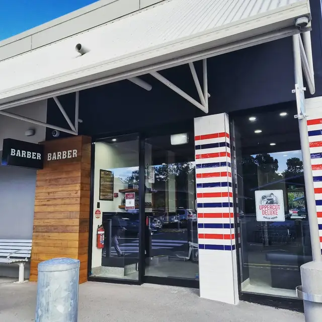 The black shopfront with red, white and navy barber poles